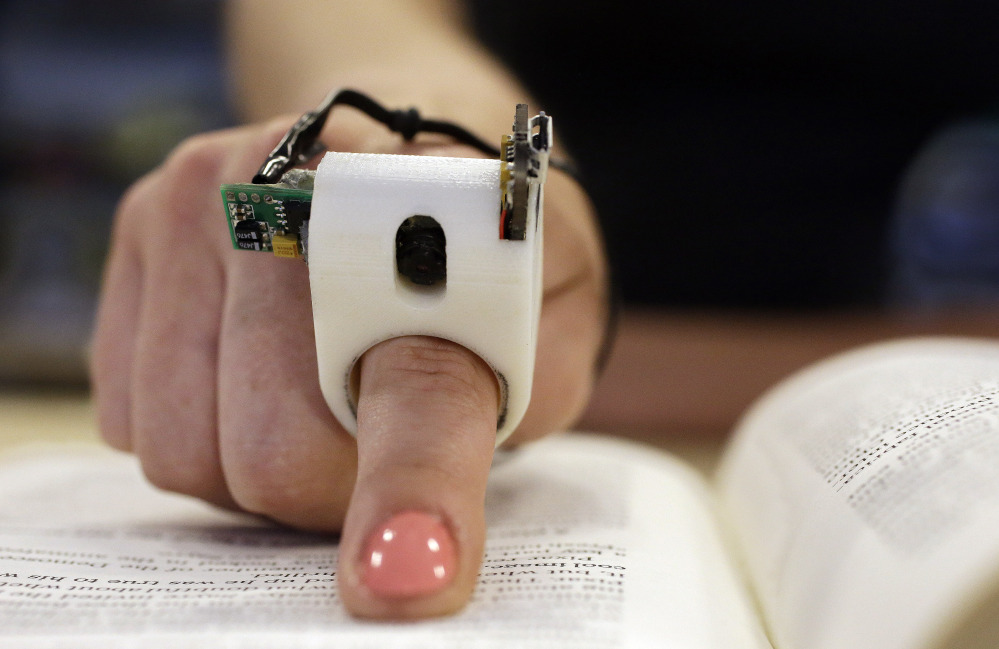 In this Thursday, June 26, 2014 photo, a model wears a FingerReader ring at the Massachusetts Institute of Technology’s Media Lab in Cambridge, Mass.