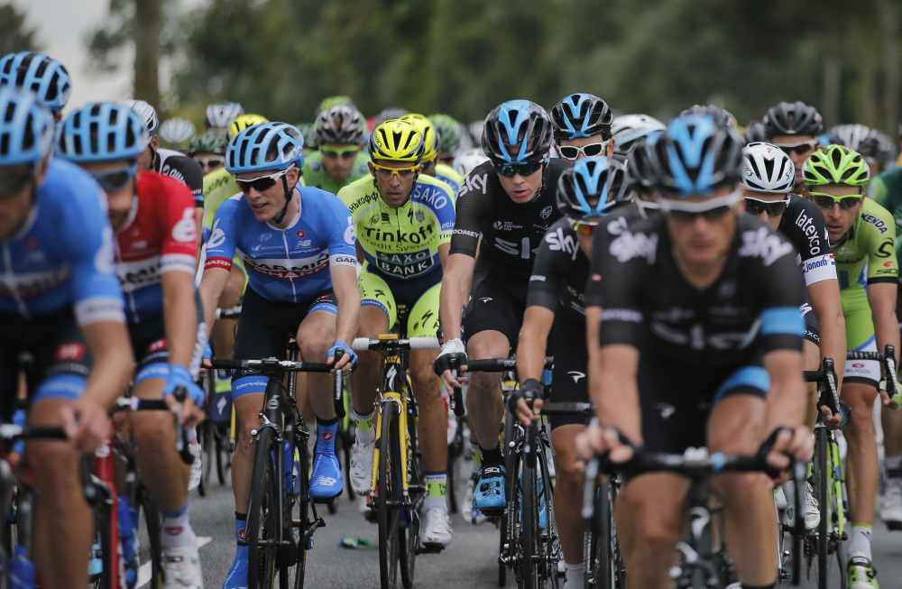 Spain’s Alberto Contador, center in fluorescent jersey, and Britain’s Christopher Froome, center with bandaged wrist, ride in the pack during the fourth stage of the Tour de France on Tuesday.