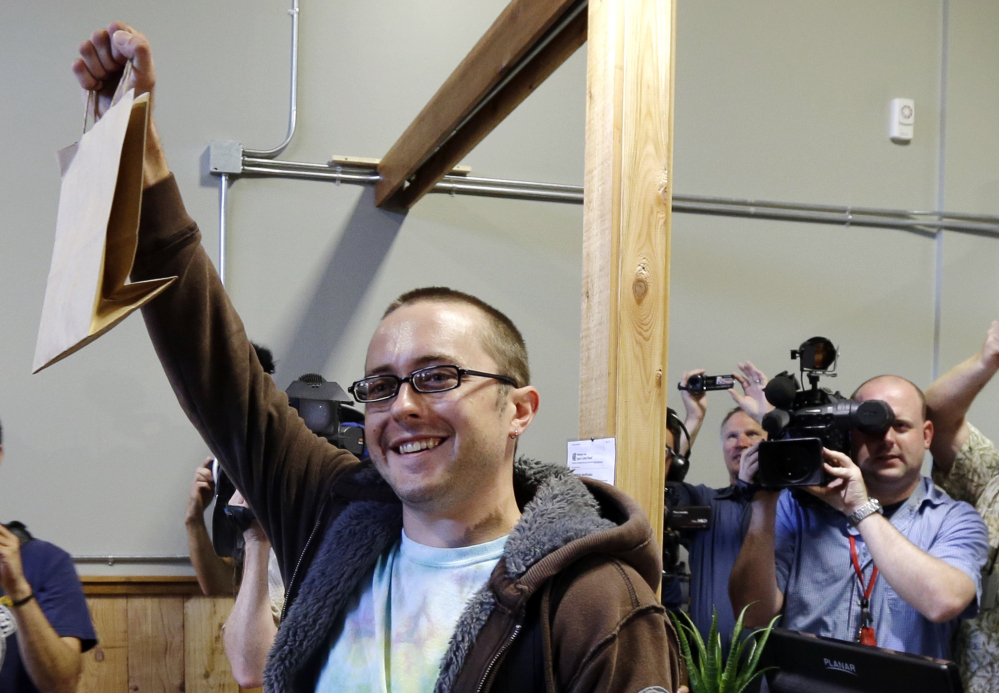 Cale Holdsworth, of Abeline, Kan., holds up his purchase after being the first in line to buy legal recreational marijuana at Top Shelf Cannabis, Tuesday in Bellingham, Wash. Holdsworth had been in line since 4:00 a.m.