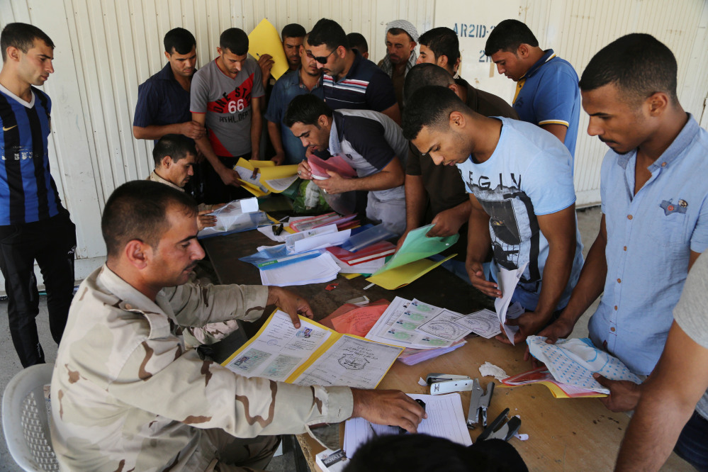 Iraqi men check in at the main army recruiting center as they volunteer for military services in Baghdad, Iraq, Wednesday.