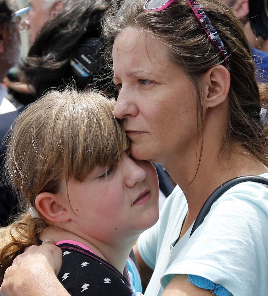 Geri Boyles of Lowell, Mass., hugs her daughter, Corinna, 10, outside a burned three-story apartment and business building in Lowell, Mass., on Thursday. 