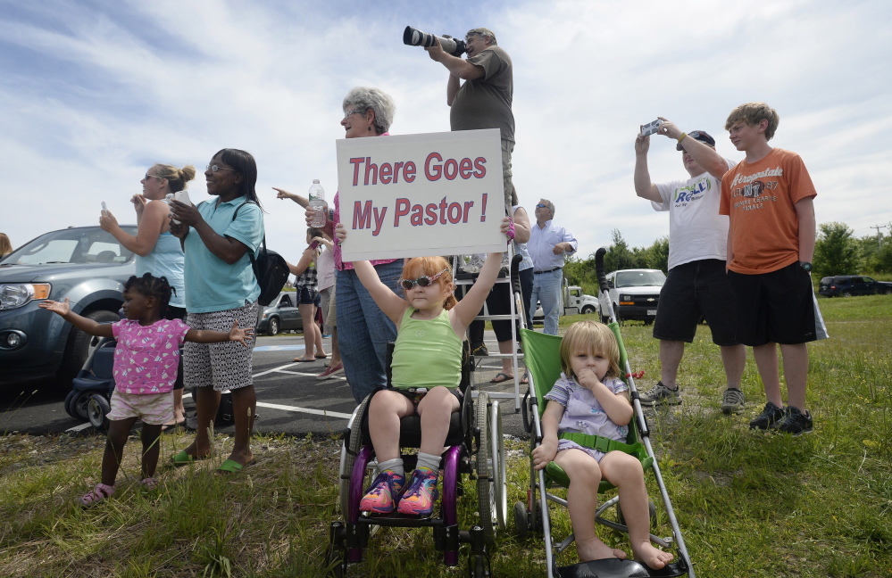 Four-year-old Sophia Emerson of Biddeford, accompanied by her 1-year-old sister, Natalie, cheers along with other congregants from The Rock Church in Scarborough as their pastor, Lt. Col. Eric Samuelson, made a final flight in an F-15, buzzing the Portland jetport Thursday. Two other F-15 pilots, top left, accompanied him on his “last mission.”