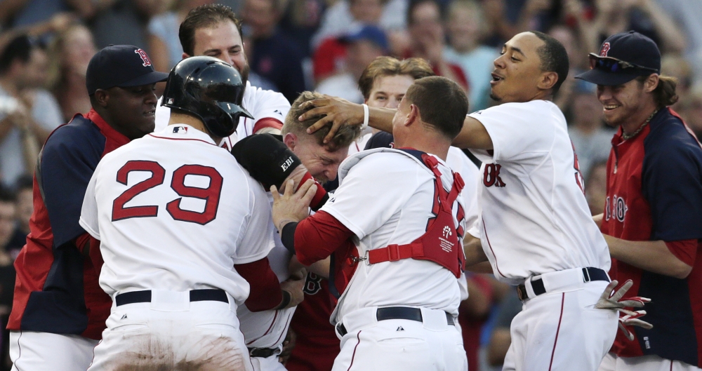 Red Sox pinch hitter Mike Carp, center, is mobbed by teammates after his walk-off RBI single, breaking a 3-3 tie against the Chicago White Sox in the 10th inning of Thursday’s game at Fenway Park.