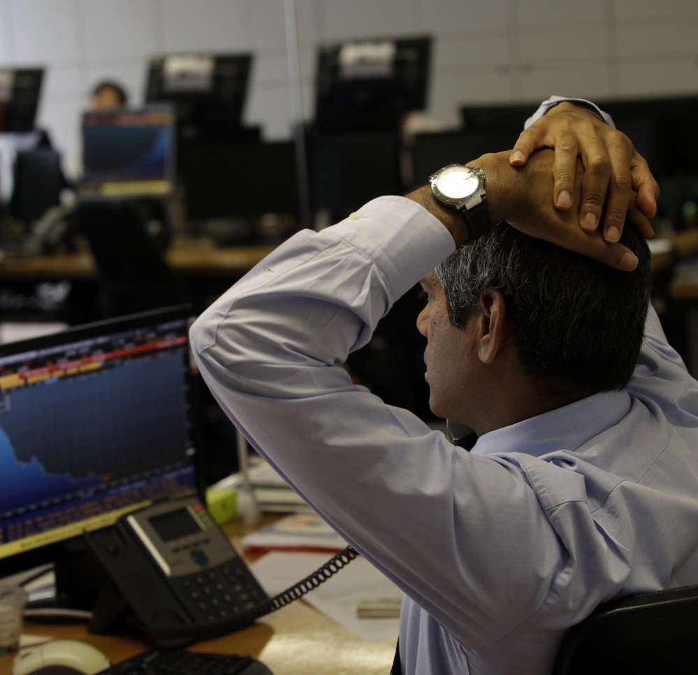 A broker stretches as he talks on the phone in a trading room at a Lisbon bank on Thursday. Share prices on the Lisbon stock exchange fell more than 4 percent.