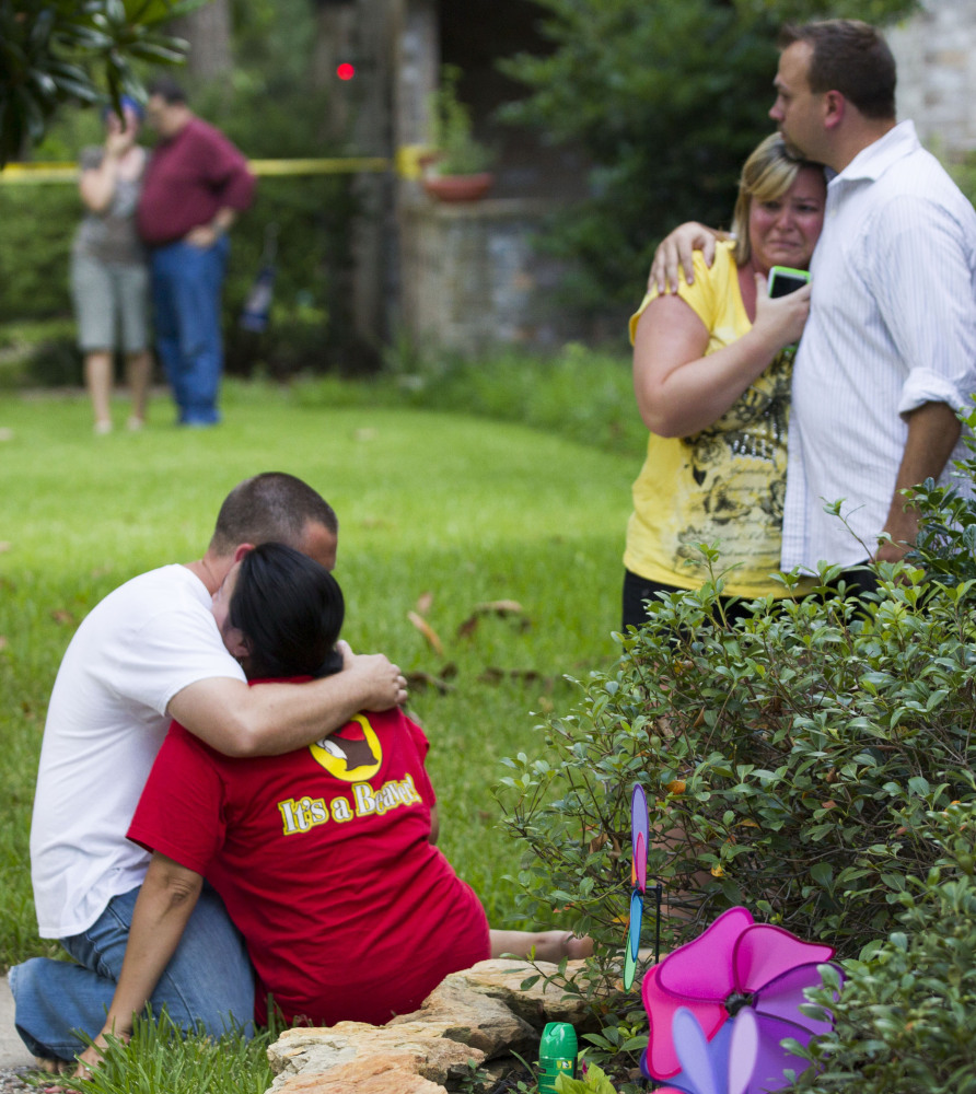 Neighbors embrace each other in suburban Houston after a shooting Wednesday, allegedly by an estranged brother-in-law, killed two parents and four of their five children.