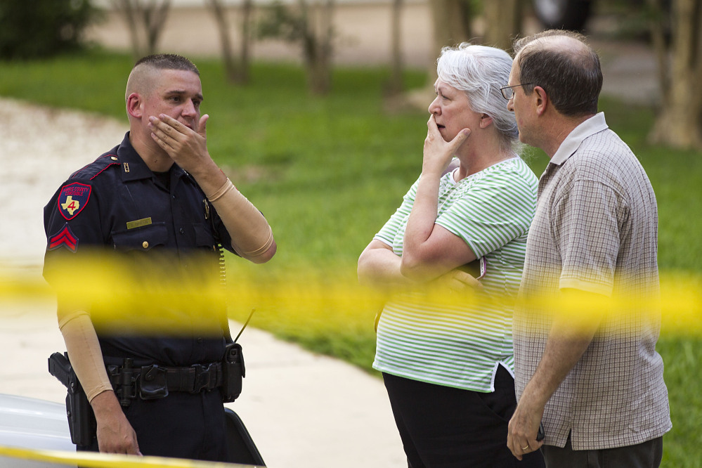 People stand with a law enforcement officer near the scene of a shooting Wednesday, July 9, 2014, in Spring, Texas. A Harris County Sheriff's Office statement says precinct deputy constables were called to the house about 6 p.m. Wednesday and found two adults and three children dead. Another child later died at a hospital. (AP Photo/Houston Chronicle, Brett Coomer)