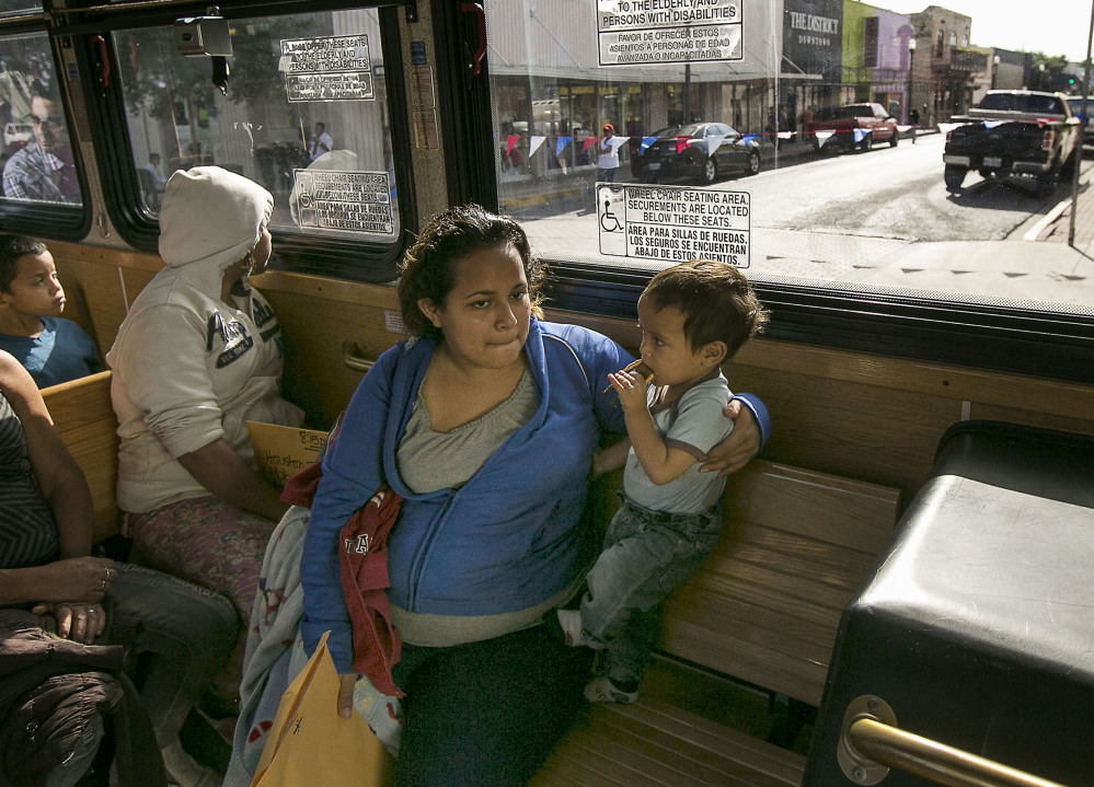 Marta Beltran, 19, of El Salvador holds her young son, Lenny, as they ride a city shuttle bus to the Sacred Heart Catholic Church Shelter in McAllen, Texas.