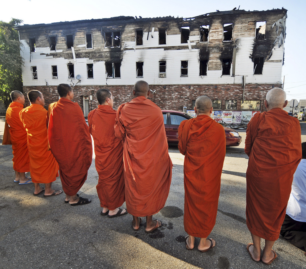 Buddhist monks pray Thursday outside a burned-out apartment building in Lowell, Mass., where seven people, including five members of a family of Cambodian descent, died in a predawn fire. Lowell is home to one of the country’s largest Cambodian communities.