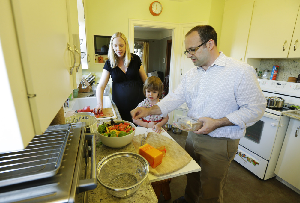 Ryan Carson, right, cooks dinner with his wife, Jenny Roraback-Carson, and their daughter Clara, 3, at their home in Seattle. 
