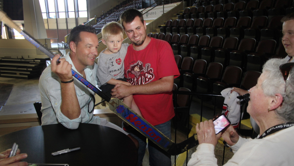 Cynthia Reed of Portland takes a photo of former Portland Pirates goalie Olaf Kolzig, left, with fan Scott Prue and Prue’s son, Westin, 3, of Biddeford during a reunion Friday of the 1993-94 Pirates team that won the franchise’s only Calder Cup championship.