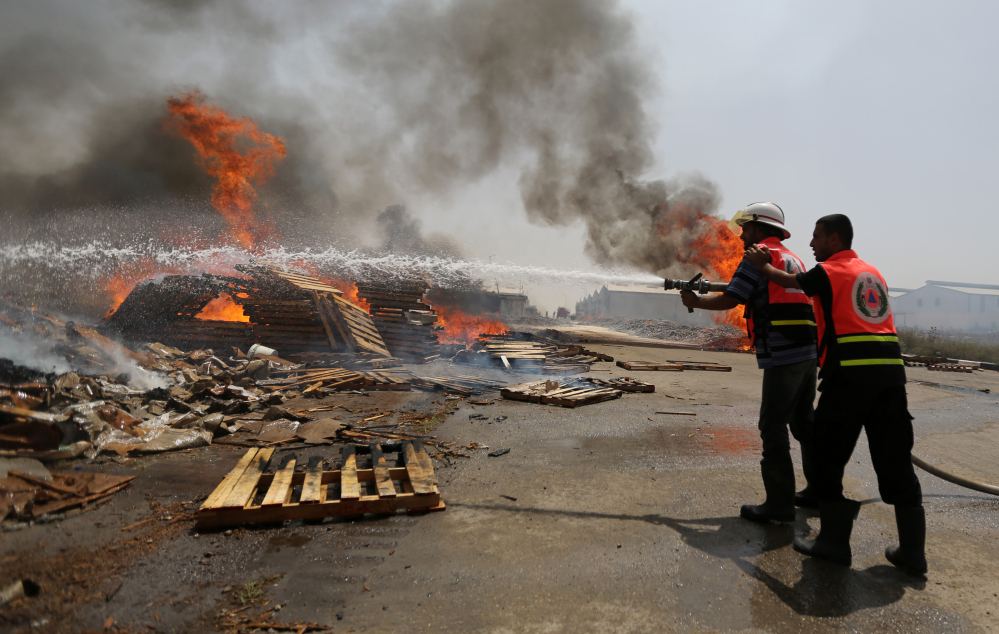 Palestinian firefighters try to extinguish a fire at a cargo terminal at Karni Crossing between Israel and Gaza after it was shelled by Israeli tanks, according to terminal’s employees, on Saturday.