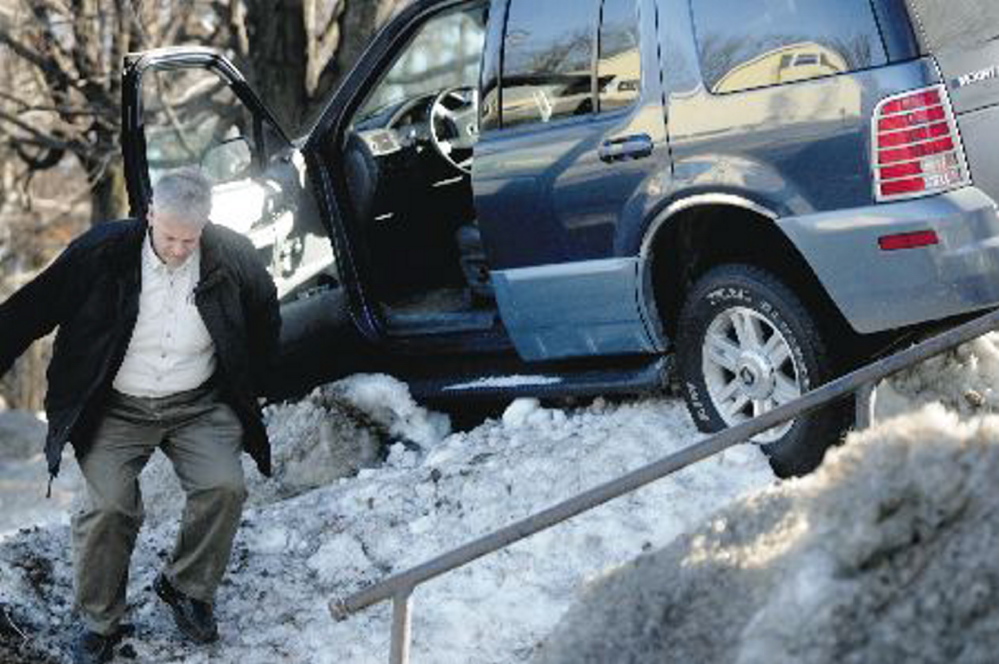 Augusta police Lt. Keith Brann leaps from an SUV he turned off after it became lodged in a snowbank in February 2010 on Western Avenue in Augusta.