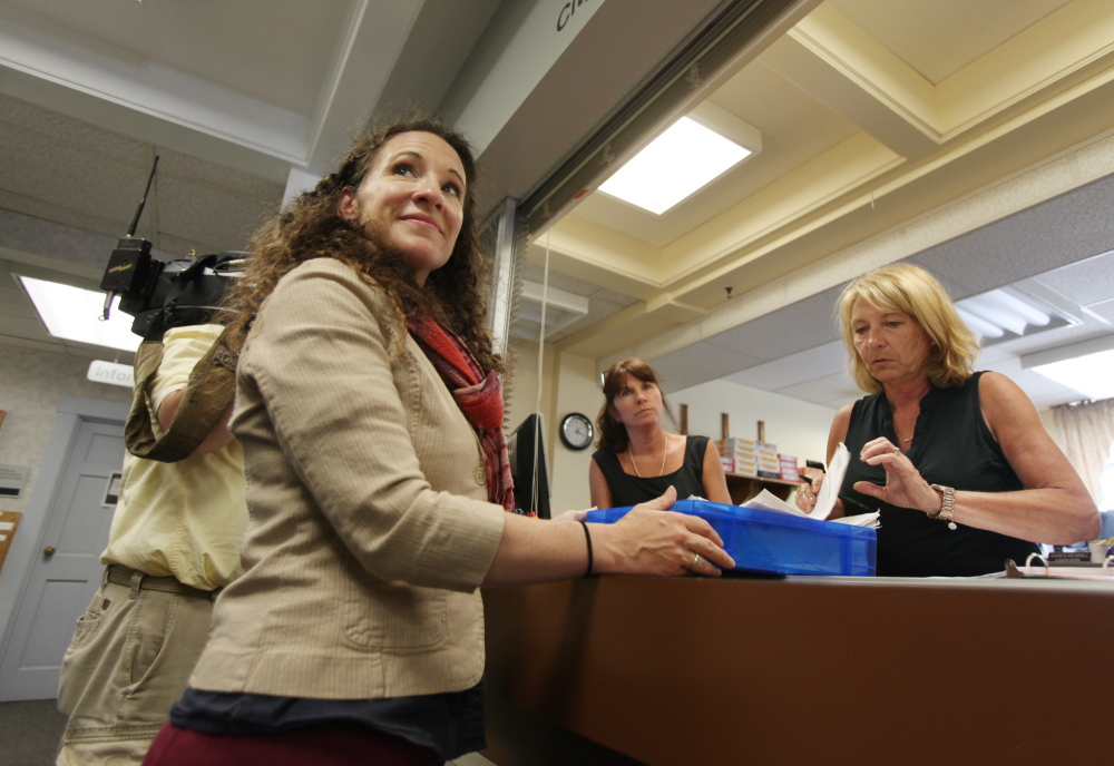 Melissa Thomas, left, turns in signed petitions to South Portland Assistant Clerk Karen Morrill, right, and Alice Kelley, center, on Monday at South Portland City Hall in South Portland. The petitions are in support of an initiative to make marijuana possession legal for adults in city limits.