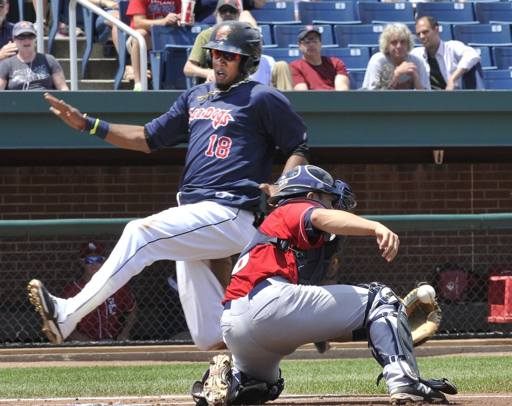 Michael Almanzar of the Portland Sea Dogs slips past catcher Derrick Chung of the New Hampshire Fisher Cats to score on a single by Jonathan Roof in the second inning Monday.