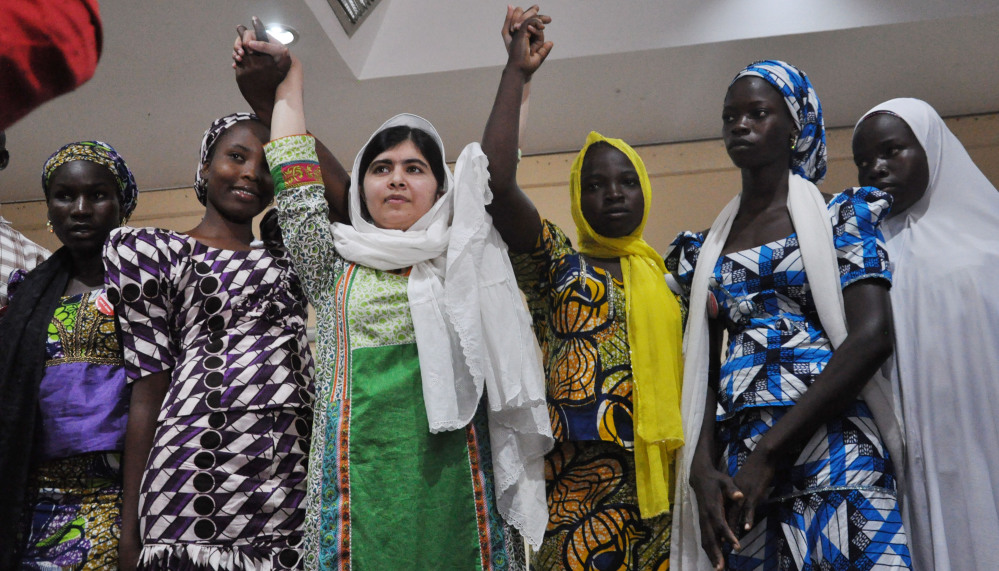 Malala Yousafzai, center, raises her hands with some of the escaped kidnapped girls at a news conference in Abuja, Nigeria, on Monday.