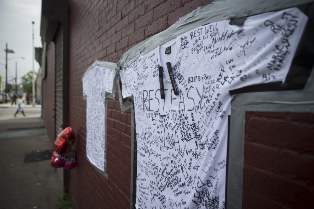 T-shirts covered with written messages are taped on a wall at memorial to Lawrence Campbell, who allegedly shot and killed 23-year-old Jersey City police officer Melvin Santiago, Monday, July 14, 2014, in Jersey City, N.J. Campbell was also killed at the scene after police officers returned fire. (AP Photo/John Minchillo)