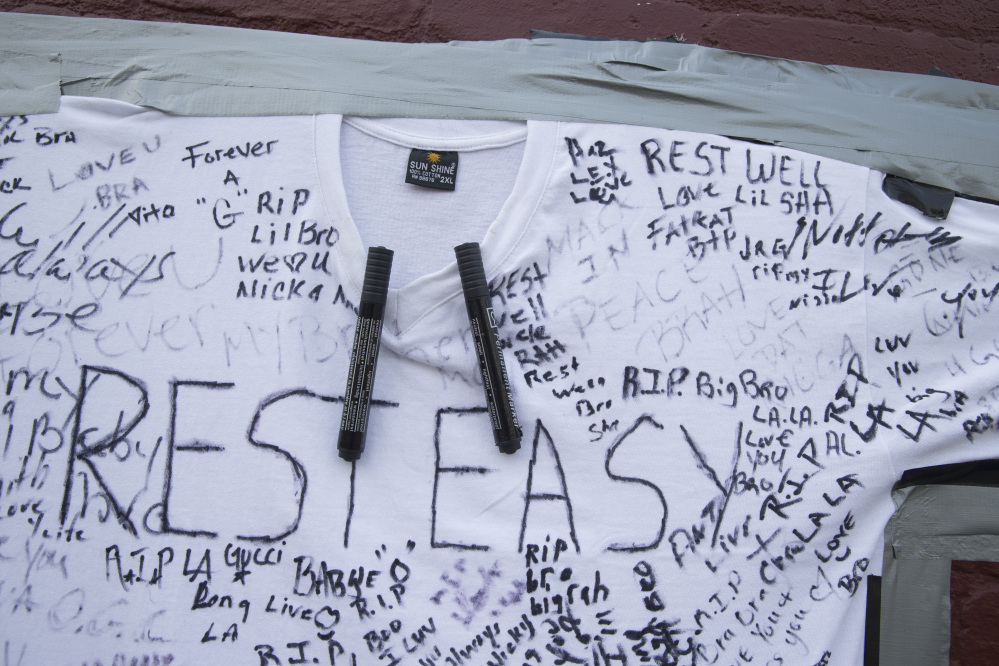 A t-shirt covered with written messages are taped on a wall at memorial to Lawrence Campbell, who allegedly shot and killed 23-year-old Jersey City police officer Melvin Santiago, Monday, July 14, 2014, in Jersey City, N.J. Campbell was also killed at the scene after police officers returned fire. (AP Photo/John Minchillo)