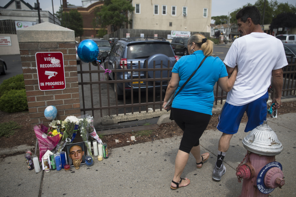 Pedestrians walk past a memorial for 23-year-old Jersey City police officer Melvin Santiago outside the Walgreens where he was fatally shot the previous day, Monday, July 14, 2014, in Jersey City, N.J. Santiago, who joined the force last July and was sworn in December, was fatally shot in the head inside his marked police car as he pulled up to the store. (AP Photo/John Minchillo)