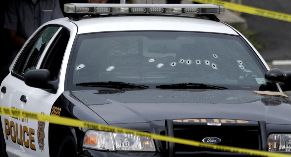 A Jersey City Police Department cruiser is seen with bullet holes on the windshield at the scene where an officer was shot and killed while responding to a call at a 24-hour pharmacy, Sunday, July 13, 2014, in Jersey City, N.J.  Officer Melvin Santiago was shot in the head while still in his police vehicle as he and his partner responded to an armed robbery call  at about 4.a.m., Jersey City Mayor Steven Fulop said in a statement.  Fulop said officers responding to the robbery call shot and killed the man who shot Santiago. He was not immediately identified. (AP Photo/Julio Cortez)