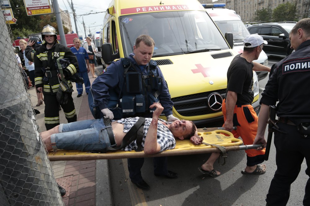Paramedics and a police officer carry an injured man out from a subway station after a rush-hour subway train derailment in Moscow, on Tuesday. Several cars left the track in the tunnel after a power surge triggered an alarm, which caused the train to stop abruptly.
