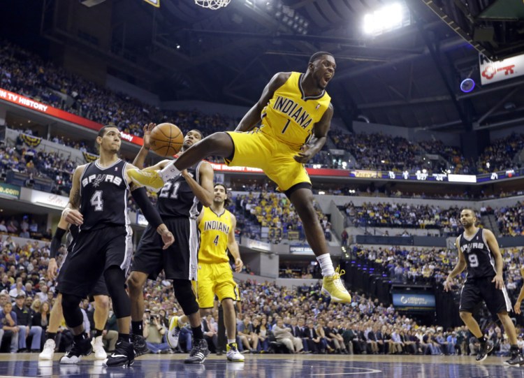 In this March 31, 2014, file photo, Indiana Pacers guard Lance Stephenson (1) reacts after a slam dunk over San Antonio Spurs guard Danny Green (4) and forward Tim Duncan (21) during the first half of an NBA basketball game in Indianapolis.