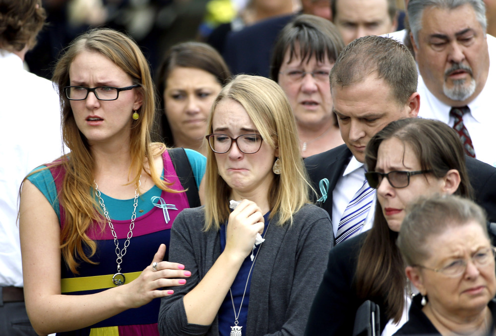 Cassidy Stay, center, watches as her family’s caskets are loaded into a hearse after a funeral in Houston. She identified her aunt’s ex, Ronald Lee Haskell, as the gunman.