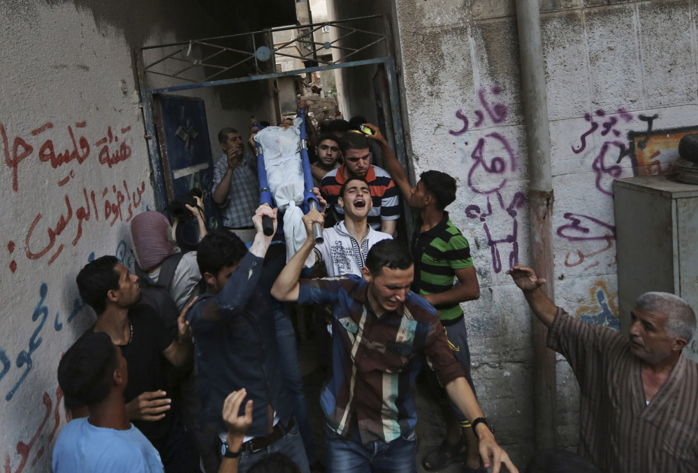 Mourners carry a Palestinian boy, one of three children killed by an Israeli missile strike earlier, outside the family house during their funeral in Gaza City on Thursday. The children were killed while feeding pigeons on the roof of their house in the Sabra neighborhood of Gaza City, the family said.