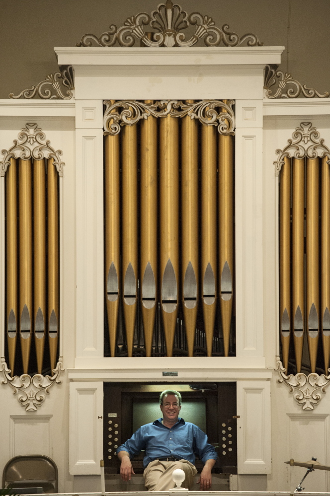 Aaron Robinson with the Damariscotta Baptist Church organ, which he was helping to restore.