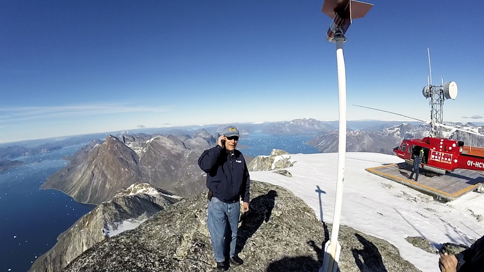 Peter Vigue stands on the top of Mount Qingaq, a 5,300-foot-high mountain peak in southwestern Greenland. From here, one can see valleys where roads will have to be built to access the iron ore mine being developed by London Mining. Frame grab from a video shot by Larus Isfeld, General Manager of Eimskip USA
