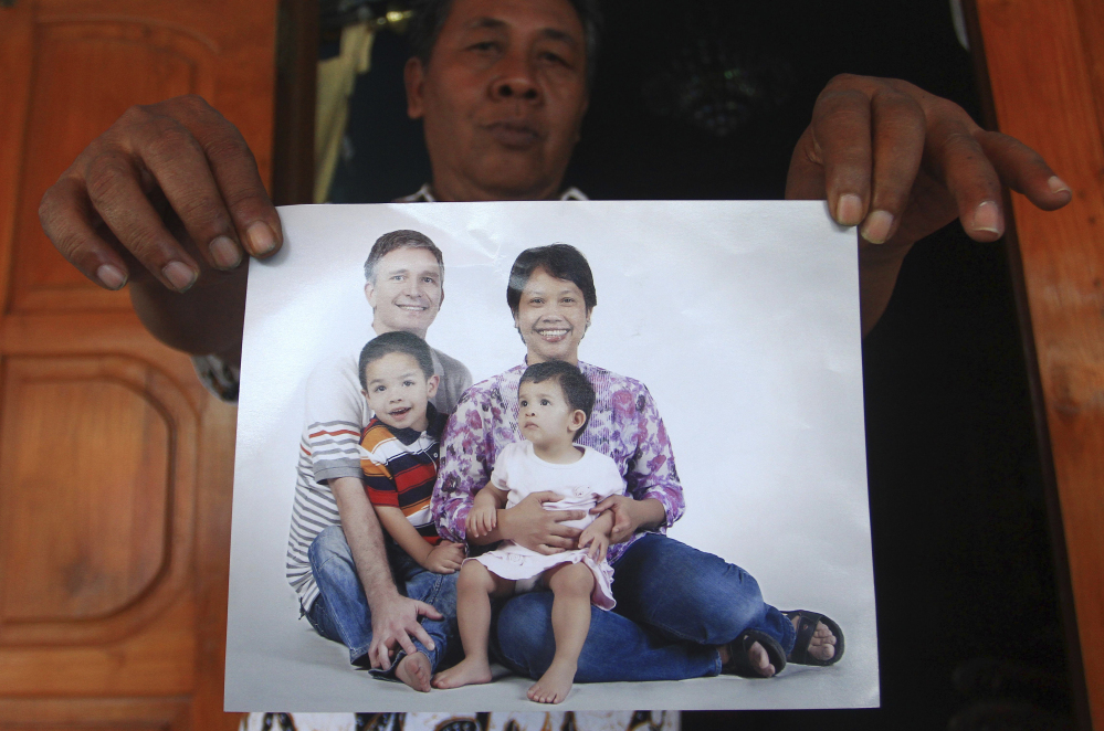 Widi Yuwono, the brother of Yuli Hastini, holds a photograph of his sister’s family – showing Hastini, right, her Dutch husband John Paulissen, left, and their two children, Arjun and Sri – who were on Malaysia Airlines Flight 17 on Friday. He displayed the photo at his residence in Solo, Central Java, Indonesia.