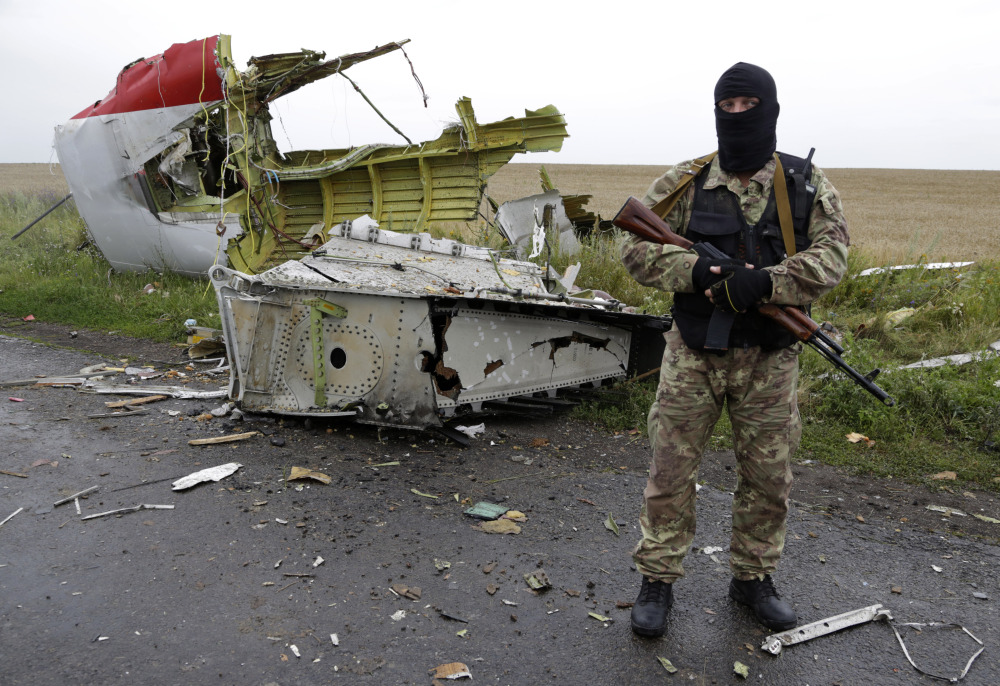 A Pro-Russian fighter stands guard at the site of a crashed Malaysia Airlines passenger plane near the village of Hrabove in eastern Ukraine on Friday. Rescue workers, policemen and even off-duty coal miners were combing a sprawling area in eastern Ukraine near the Russian border where the Malaysian plane ended up in burning pieces Thursday, killing all 298 aboard.