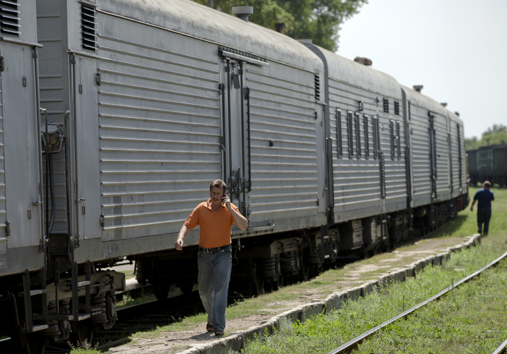 A man speaks on a phone as he walks next to a refrigerated train loaded with the bodies of victims of the Malaysia Airlines Flight 17 crash in Torez, eastern Ukraine on Sunday.