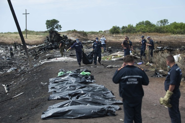 Ukrainian emergency workers carry a victim’s body in a bag as pro-Russian fighters stand guard at the crash site of Malaysia Airlines Flight 17 near the village of Hrabove, eastern Ukraine, Sunday.