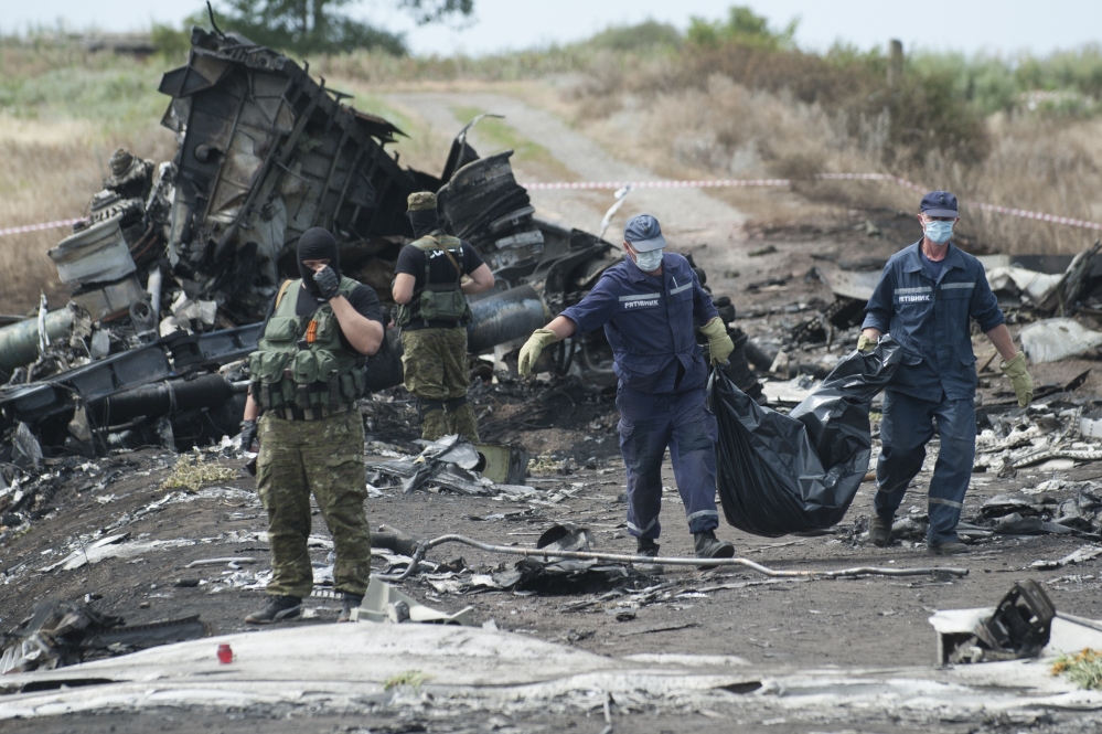 Ukrainian emergency workers carry a stretcher with a victim’s body in a bag as pro-Russian fighters stand guard at the crash site of Malaysia Airlines Flight 17 near the village of Hrabove, eastern Ukraine, on Sunday.