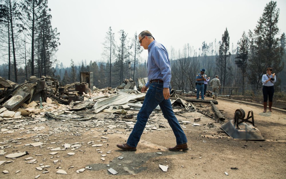 Washington state Gov. Jay Inslee walks the perimeter of a burned-down home during a visit to residential areas affected by the Carlton Complex wildfire near Malott, Wash., on Sunday. The wildfire now covers more than 370 square miles.