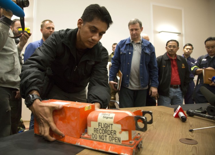 A Malaysian investigator takes a black box from Malaysia Airlines Flight 17 as it is handed over from Donetsk People’s Republic officials to Malaysian representatives in the city of Donetsk, eastern Ukraine, on Tuesday.