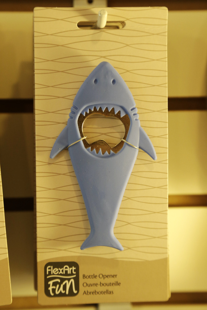 A bottle opener in the likeness of a shark hangs from a hook in a souvenir shop in Chatham, Mass.