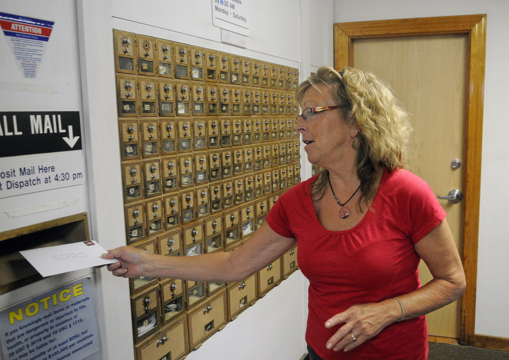 Anne Merrill mails a letter last month at the post office in North Monmouth. The U.S. Postal Service plans to reduce weekday hours there to four hours per day. A public meeting on the plan is scheduled for Tuesday.