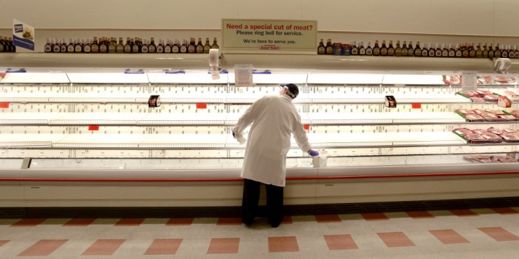 Robert Barclay, a meat department worker at the Market Basket in Biddeford, keeps busy Monday by cleaning the empty shelves usually stocked with chicken products. Workers have protested the firing of a CEO by refusing to make deliveries, leaving stores understocked.
