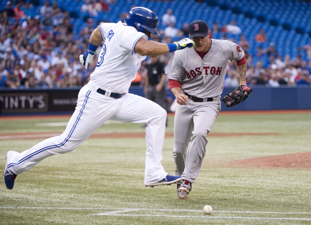 Toronto Blue Jays’ Melky Cabrera, left, runs past Boston Red Sox starting pitcher Jake Peavy, beating a wild throw at first base, but was tagged out at second in a run down during the third inning Tuesday’s game in Toronto.
