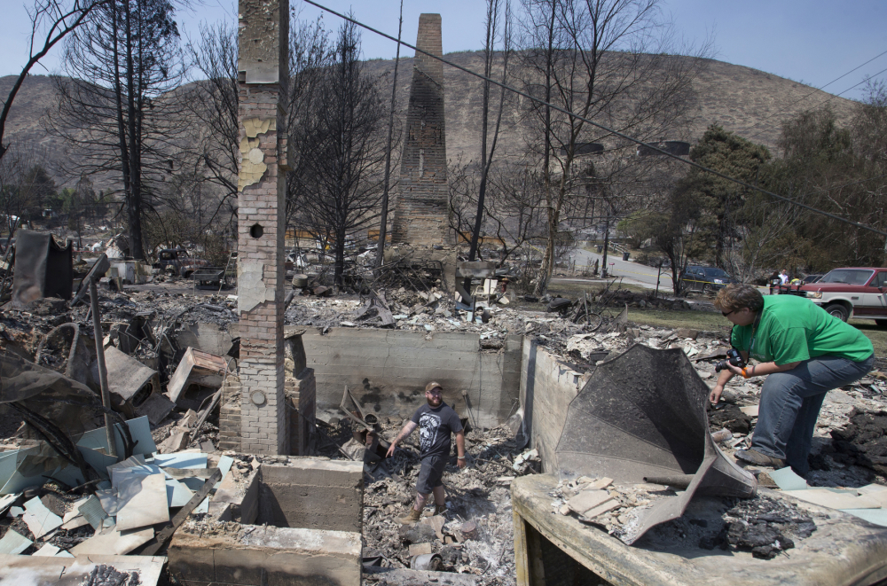 Jake Hixon, center and Kathy Harding look for family heirlooms they may have been spared at a relative’s house Monday after the fire that swept through Pateros, Wash. 
