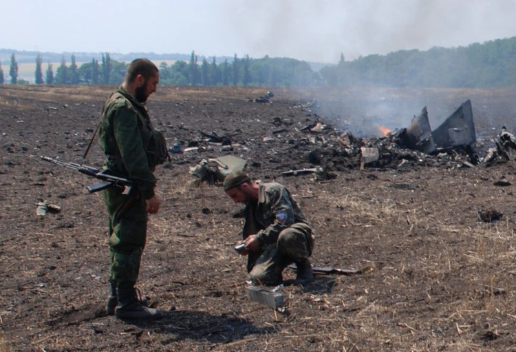 The Associated Press
In this framegrab made from a video provided by press service of the rebel Donetsk People’s Republic and icorpus.ru,  pro-Russians collect parts of the burning debris of a Ukrainian military fighter jet, shot down at Savur Mogila, eastern Ukraine, Wednesday.