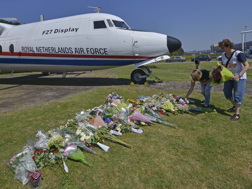 People lay flowers in front of a plane prior a ceremony to mark the return of the first bodies, of passengers and crew killed in the downing of Malaysia Airlines Flight 17, from Ukraine at Eindhoven military air base, Wednesday.