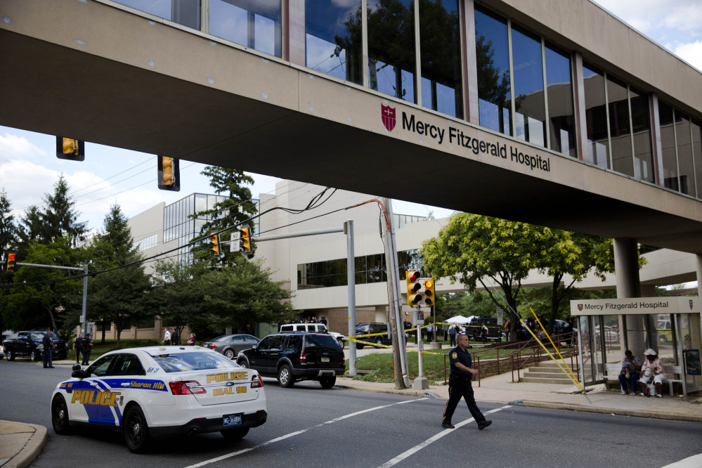 An officer walks near the scene of a shooting Thursday at Mercy Fitzgerald Hospital in Darby, Pa. A shooting at a suburban Philadelphia hospital campus killed one worker and injured two other people.
