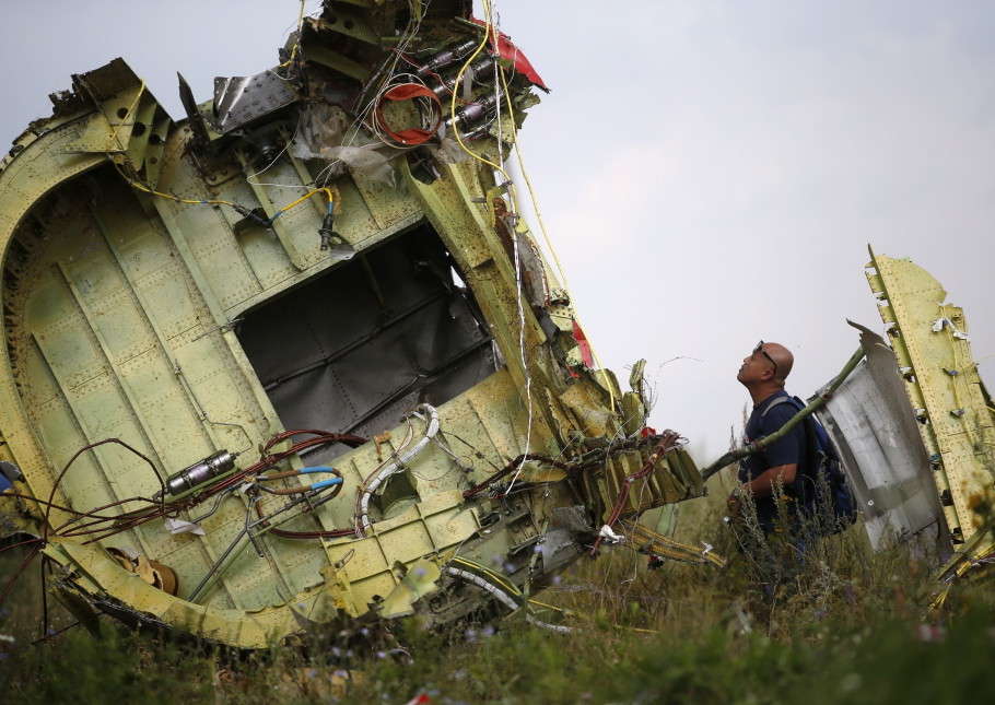 An official inspects a piece of the Malaysia Airlines plane shot down in Ukraine. It was one of three tragedies in a harrowing week for air travel.