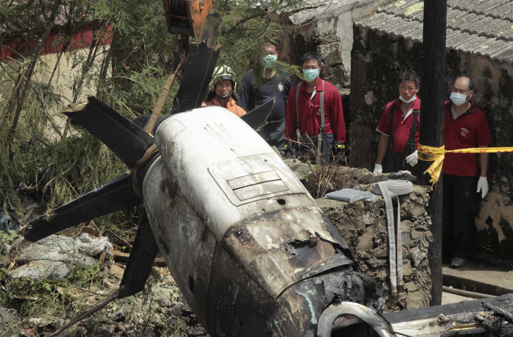 Emergency workers watch an engine lifted from the TransAsia Airways Flight GE222 crash site on the outlying Taiwan island of Penghu on Friday. Investigators were examining wreckage and flight data recorders for clues into a plane crash on the Taiwanese island that killed 48 people.
