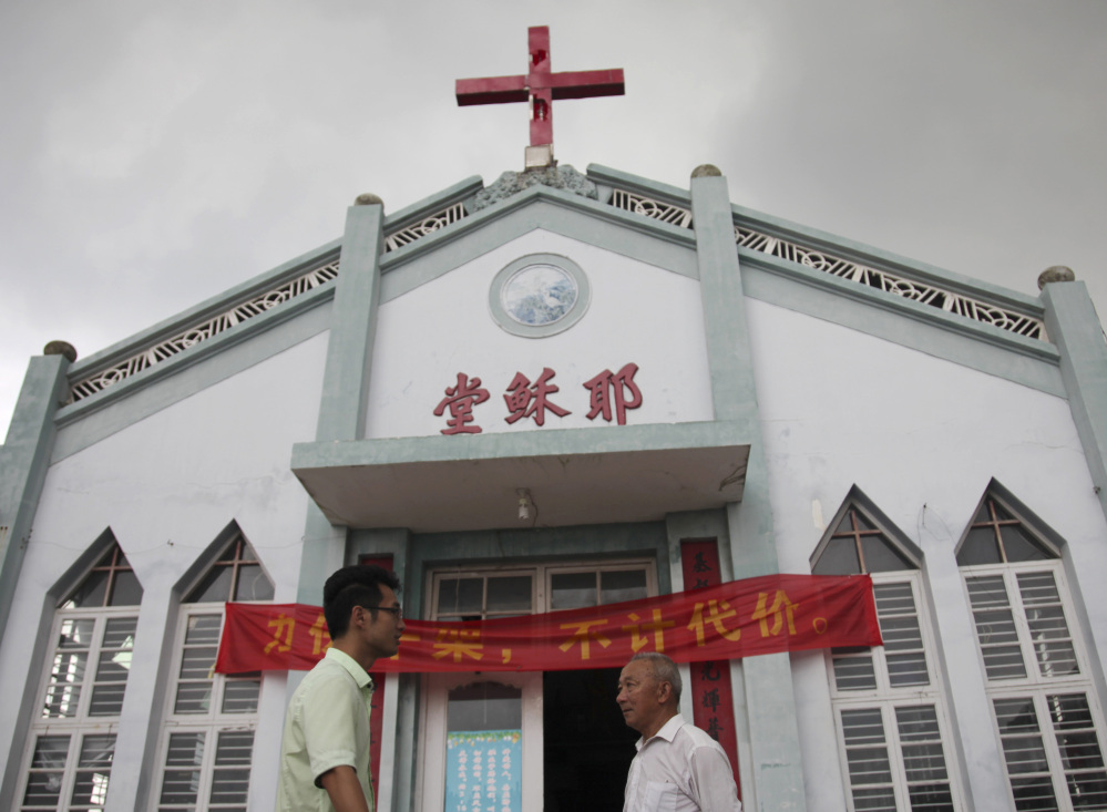 Pastor Tao Chongyin, left, speaks with Fan Liang’an in front of the Wuxi Christian Church in Longwan, Wenzhou, in eastern China’s Zhejiang province. “I won’t let them take down the cross even if it means they would shoot me dead,” said Liang’an.