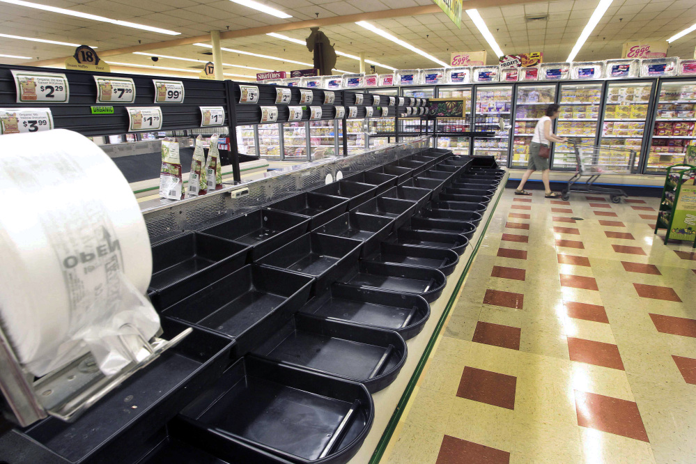 A customer walks by the empty produce aisle Thursday at a Market Basket in Concord, N.H. The Associated Press