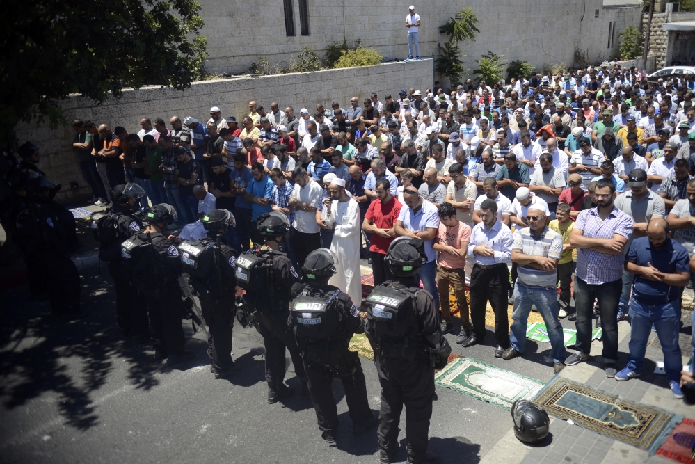 Israeli police officers stand in front of  Palestinian worshippers who were prevented from reaching the Al-Aqsa Mosque as they pray outside Jerusalem’s Old City on Friday.