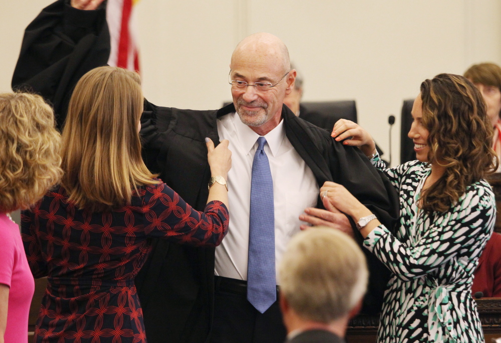 U.S. District Judge Jon David Levy of Portland gets some help  putting on his new robes from his daughters, Rachel Levy, left, and Anna Prager, during a ceremony Friday in Portland, where he was formally sworn in to the federal bench.